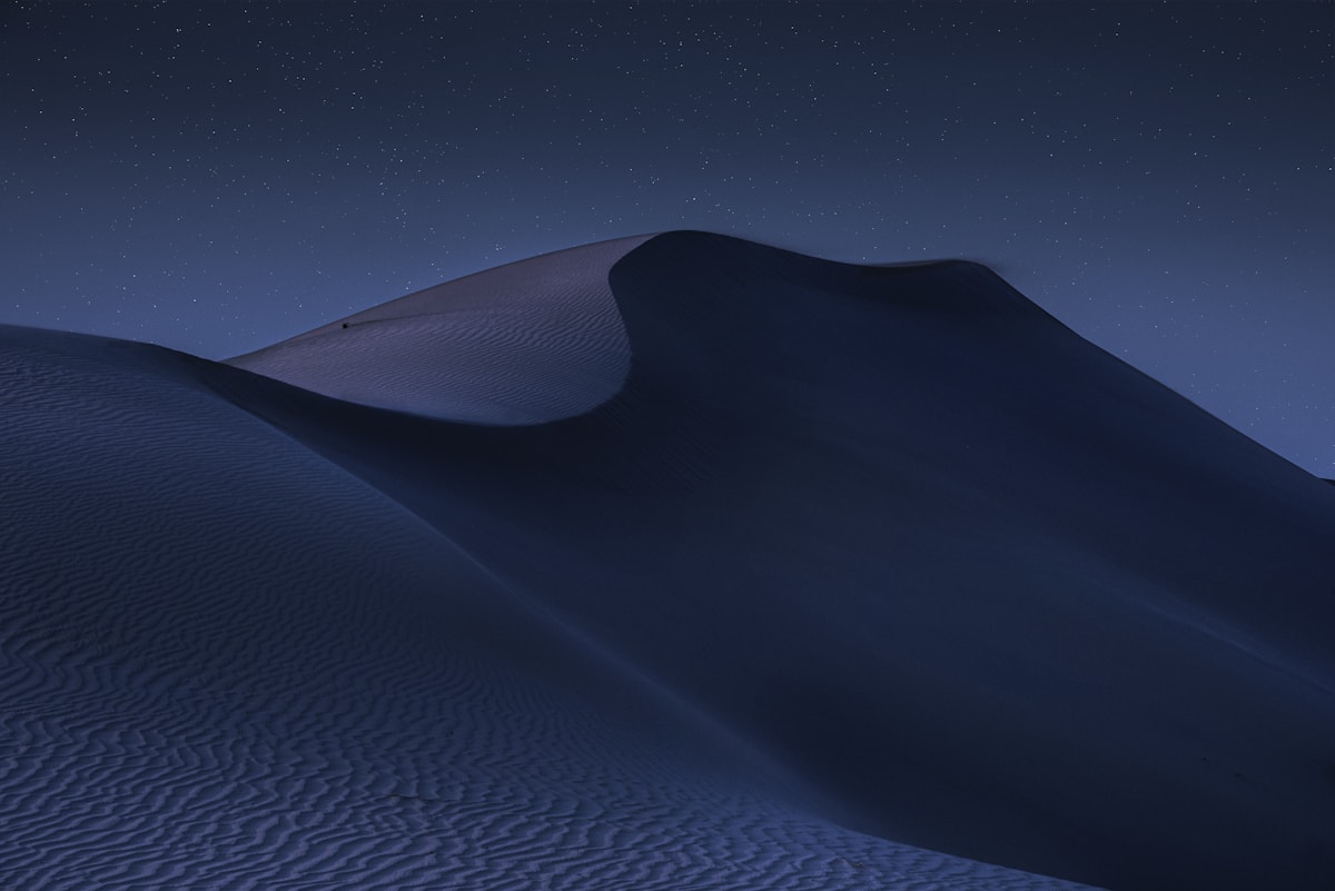 Sand dunes under a starry night sky